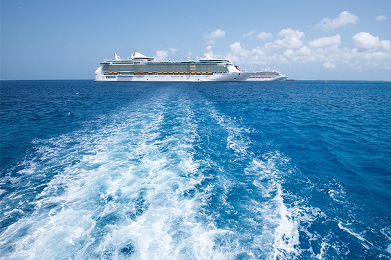 Wake from a tender boat, with cruise ships in the distance