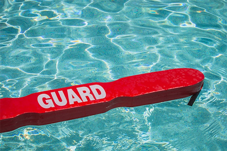 A close up shot of a life guards red rescue tube floating in a pool