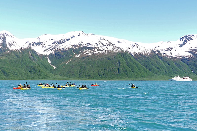 Passengers kayaking in Alaska, with mountains and Windstar ship in the background