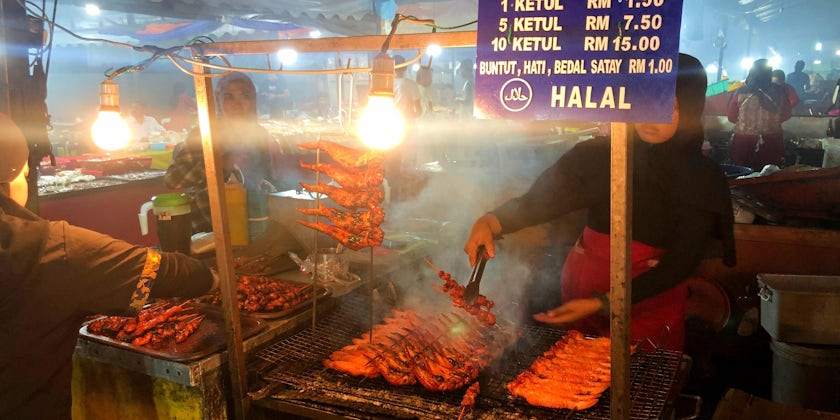 Woman serving grilled chicken butts at a night market in Kota Kinabalu, Malaysia (Photo: Adam Coulter/Cruise Critic)