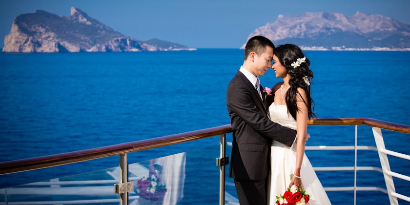 Asian couple posing in wedding attire on the sun deck on Allure of the Seas