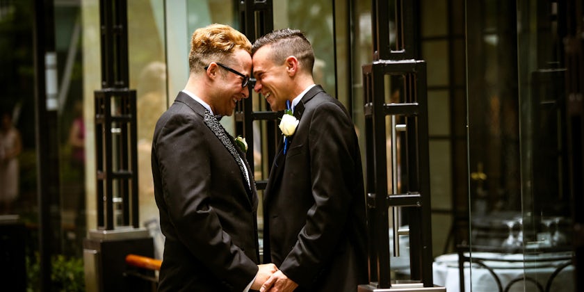 Two men smiling and holding hands on their wedding day on Oasis of the Seas