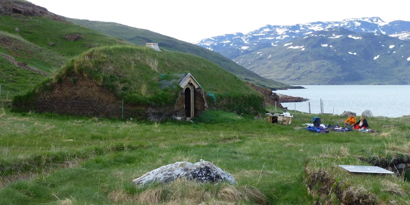 Travelers relax near one of the Reconstructed Viking Buildings at Brattahlid in Qassiarsuk, Greenland (Photo: Sarah Schlichter/Shutterstock)