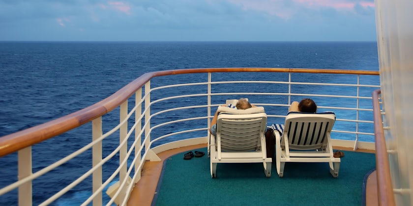 Older, retired couple lounging on deck chairs on a cruise ship sun deck