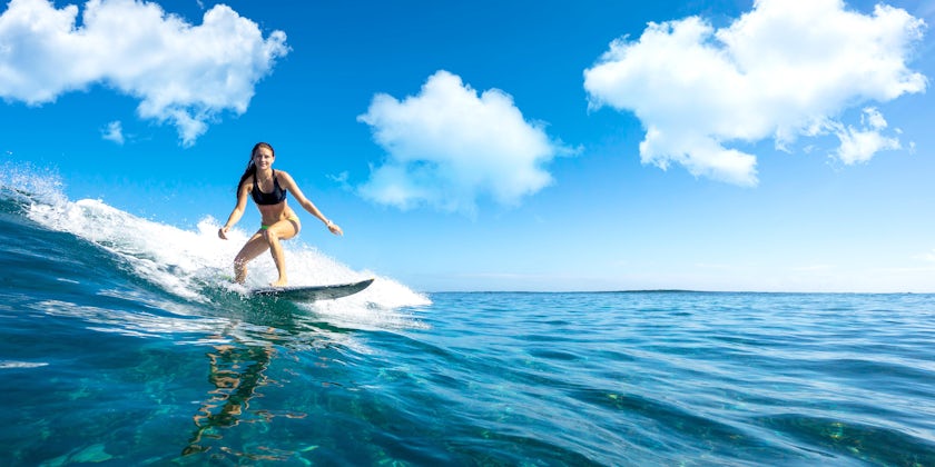 A Young Girl Surfing on a Blue Wave (Photo: ohrim/Shutterstock)