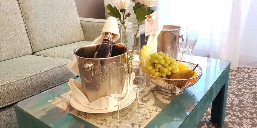 Bottle of champagne and a fruit basket in a balcony cabin living area on Boudicca (Photo: Donna Dailey)