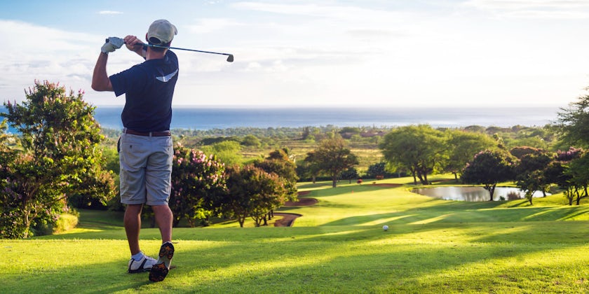 Man golfing on open field with the ocean in distance (Photo: Allen.G/Shutterstock)