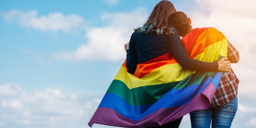 Couple wrapping the Pride Flag around them in spirit of the LGBT community (Photo: Angyalosi Beata/Shutterstock)