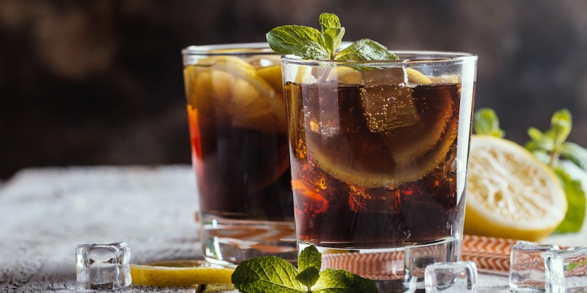 Fresh made Cuba Libre with brown rum, cola, mint and lemon on wooden background (Photo: Goskova Tatiana/Shutterstock)