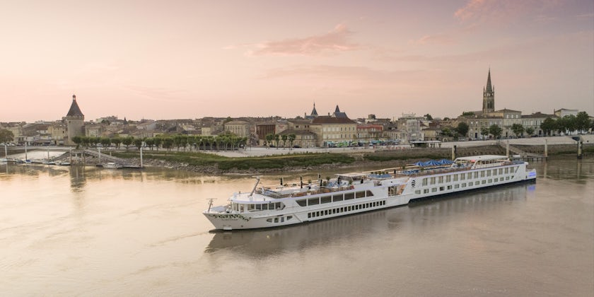 Exterior drone shot of S.S. Bon Voyage cruising along a river at sunset
