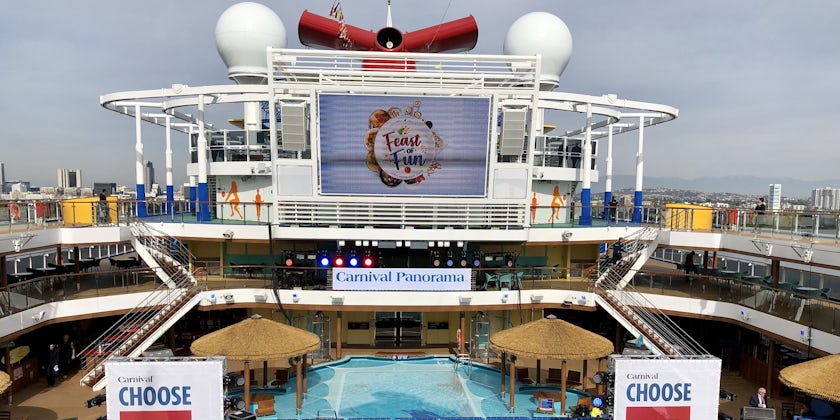 Wide-angle shot of Carnival Panorama's Pool Deck, with christening decor and stage in the frame
