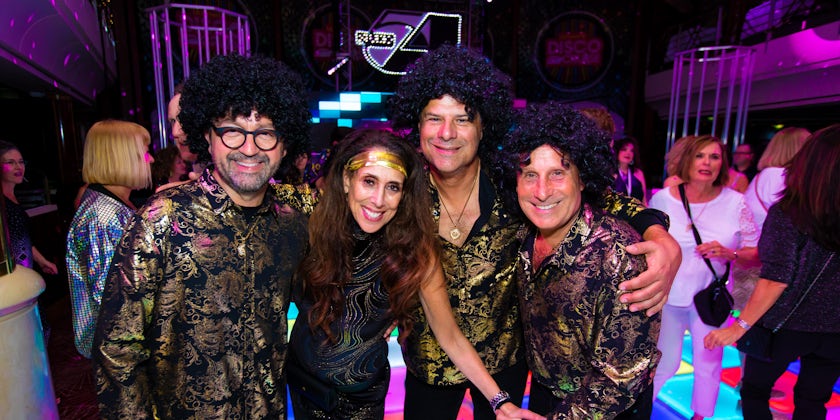 Four adult passengers dressed up in disco attire and costumes on the Ultimate Disco Cruise