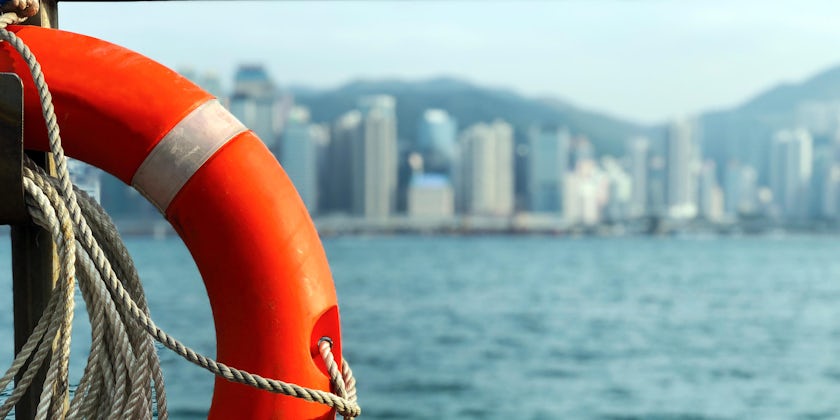 Close-up of a Life preserver ring onboard a cruise ship, with port city in the background