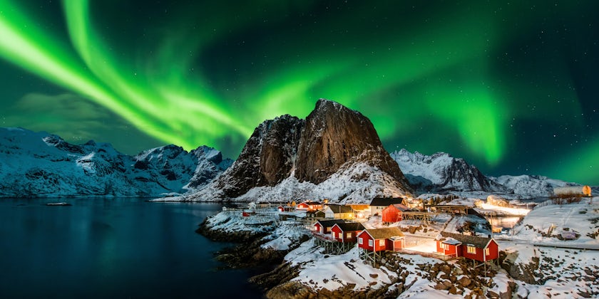 Panoramic shot of The Northern Lights over a small mountain town in Norway