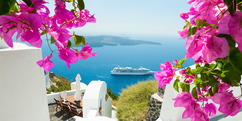 Cruise ship sailing past Santorini, from the view of white buildings and pink spring flowers