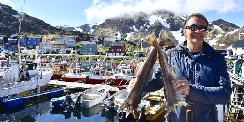 Cruise passenger posing with two fish in Fishing village outside Honningsvag, Norway