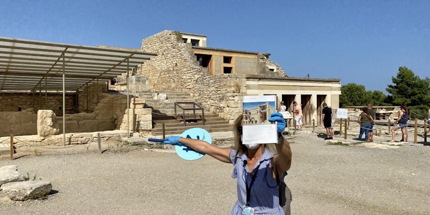 Female tour guide wearing a mask and holding up an informative sheet during a Palace of Knossos transfer tour in Crete
