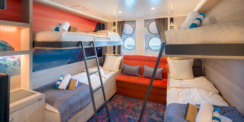 Shot of a blue, white and orange porthole cabin with bunk beds on Janssonius