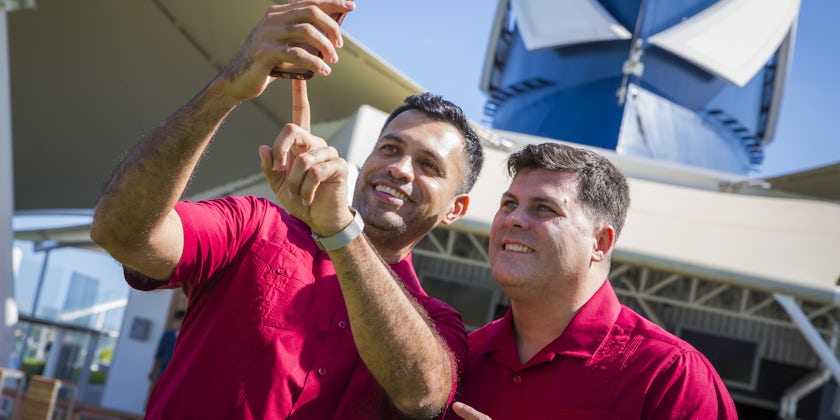A same-sex male couple taking a selfie in matching outfits before their wedding on Celebrity Cruises