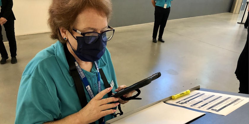 Port employee checking COVID-19 vaccine cards during embarkation