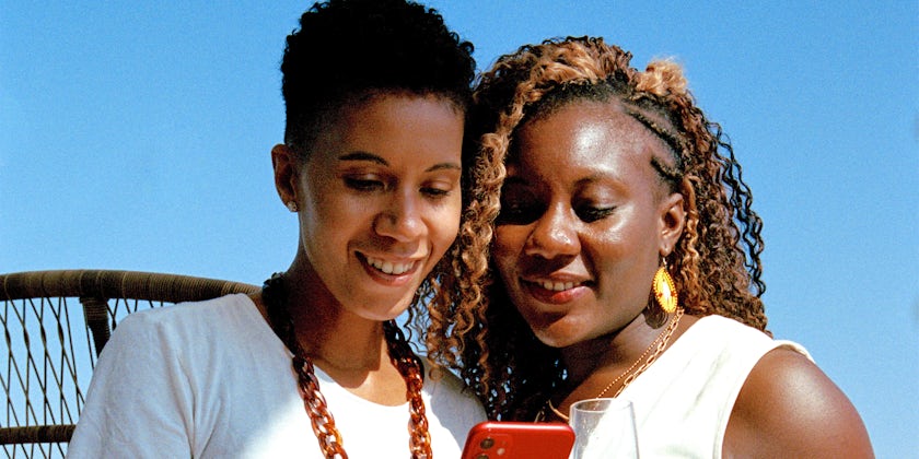 Travelers and LGBTQ+ activists Aisha and Lexie look at images on a mobile phone. (Photo: Giles Duley/AIPP)
