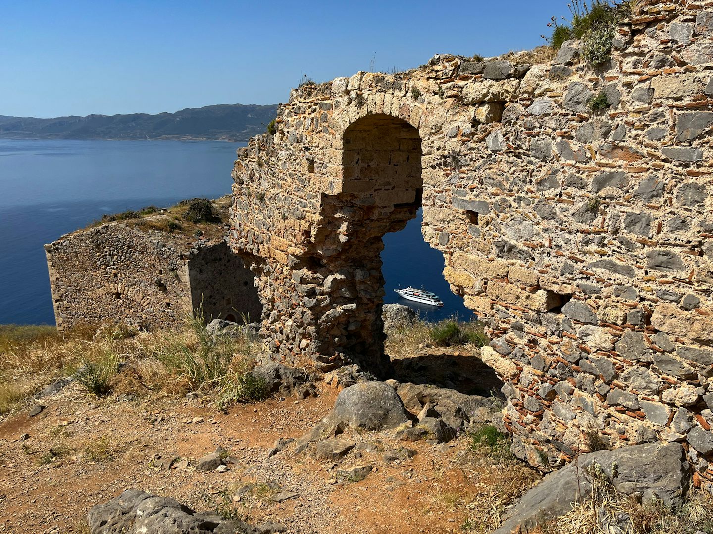 The Variety Voyager peeks through an archway on the top of Monemvasia