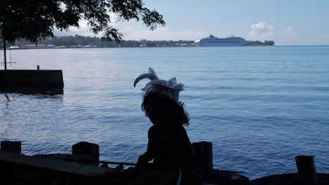 native child with ship in background.