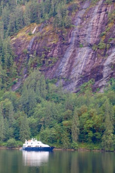 Safari Quest looking tiny next to sheer cliffs at Princess Louisa Inlet, popular summertime destination for yachts.