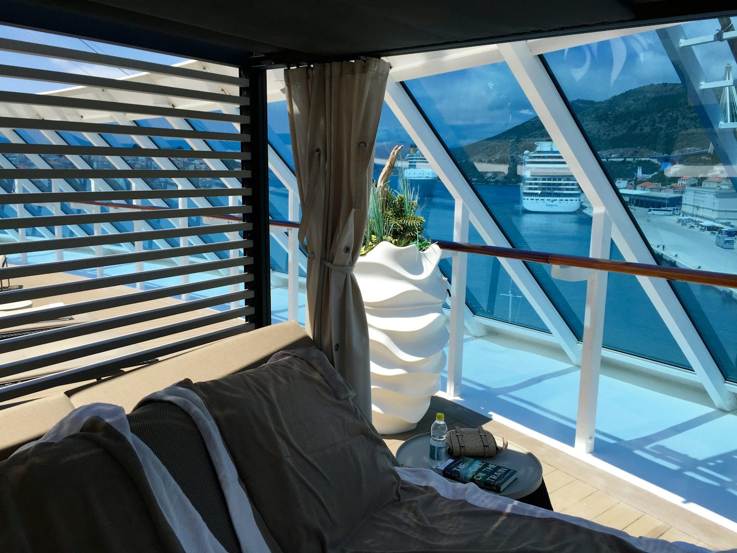 Outdoor day bed poolside at the back of the ship with elegant white drapes.
