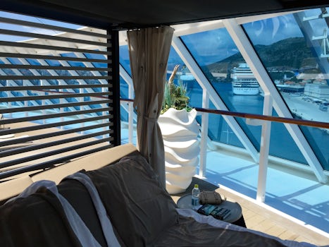 Outdoor day bed poolside at the back of the ship with elegant white drapes.
