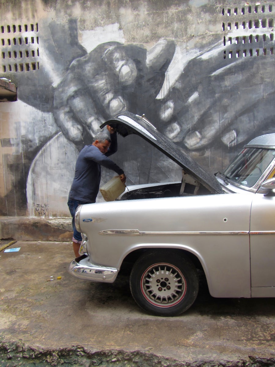 Street scene, Havana.  A lucky shot of an elderly Cuban servicing his car.