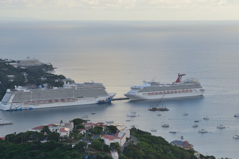Carnival Sunshine is dwarfed by Norwegian Escape at anchor in St. Thomas, U.S. Virgin Islands.