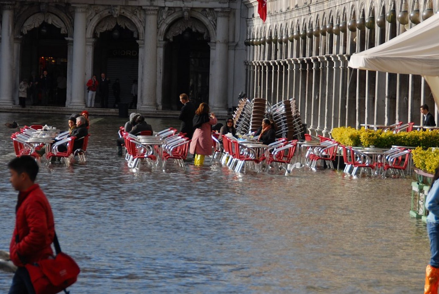 People enjoying their day at an outdoor cafe in St Marks Square in Venice during the flooding season