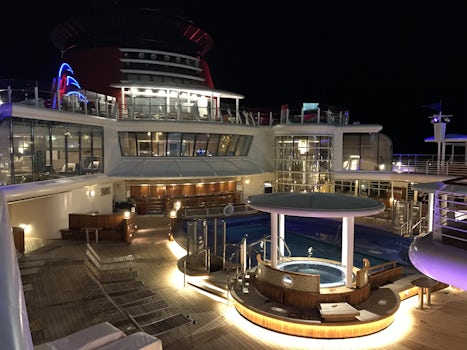 Adult pool on deck 9 at night, with concierge lounge above.
