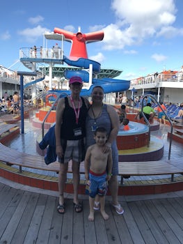 me, my daughter, and grandson in front of the pool and waterslide.