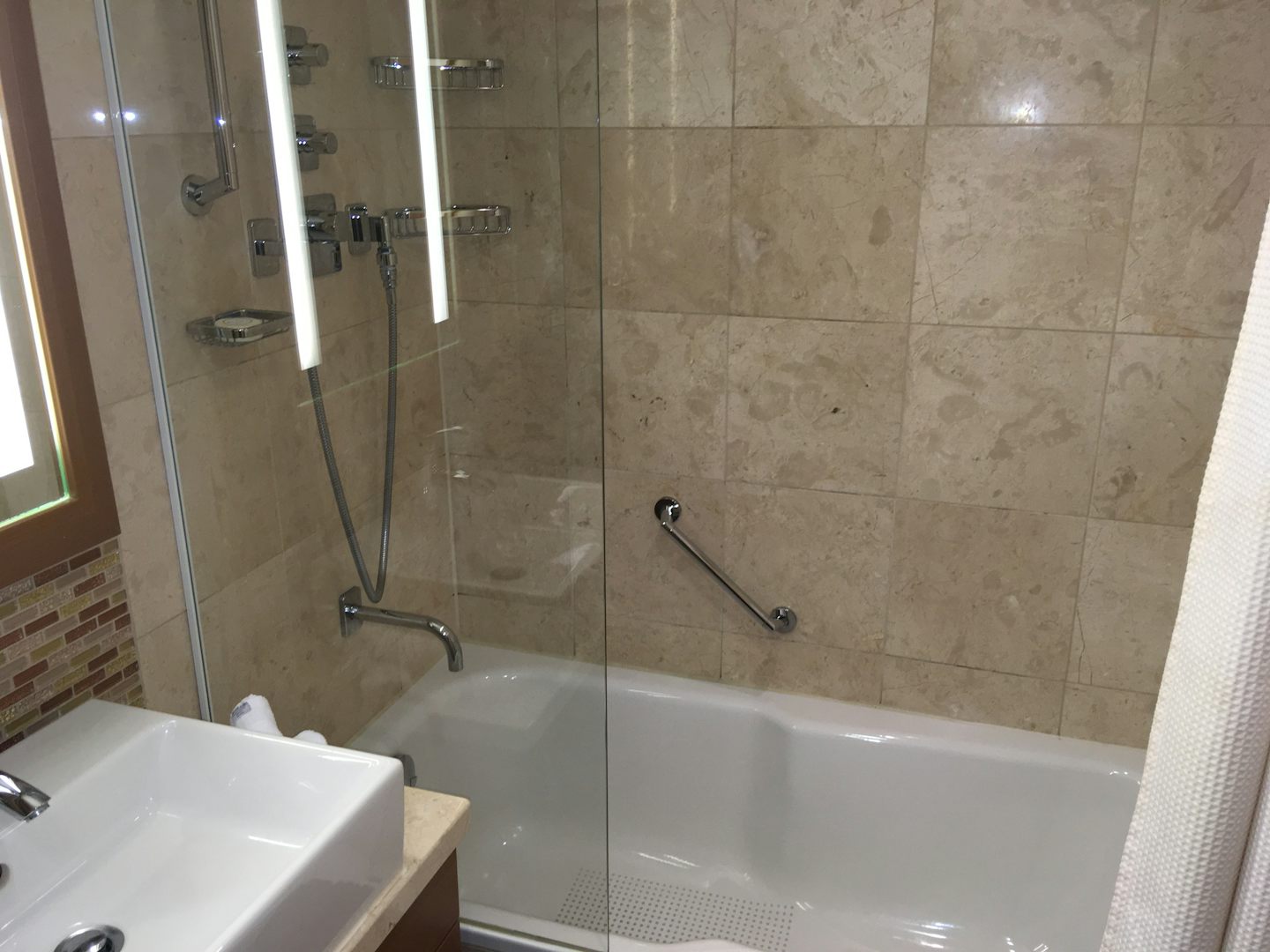 Bathroom with single sink and shower above bath. Very small as it has 2 doo