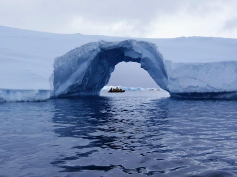 An Arch in an Iceberg with fellow passengers in a Zodiac on the other side