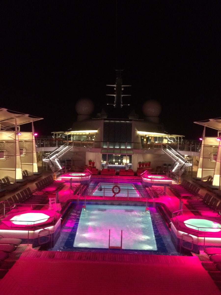 Deck 12 pools and jacuzzis lit up at night.