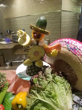 Fruit sculpture of mariachi singer in charro on the buffet line (sideways)