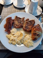 Breakfast: bacon, french toast, chocolate croissant, and scrambled eggs.
