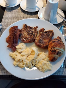 Breakfast: bacon, french toast, chocolate croissant, and scrambled eggs.