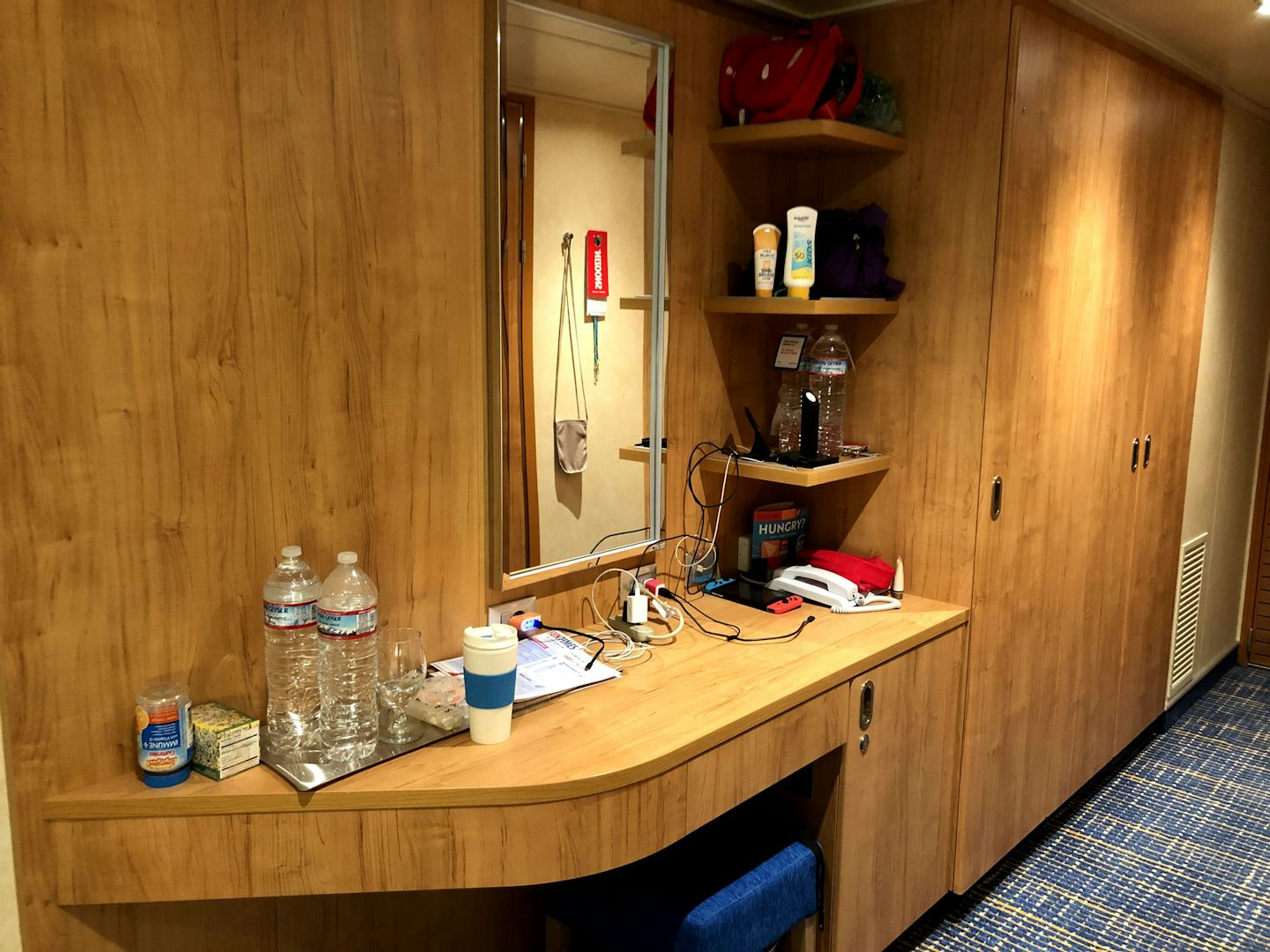 Desk/vanity, mini fridge beneath it, and closet space next to it. 