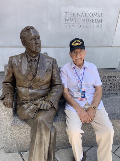 WWII Navy veteran sitting beside a statue of President Roosevelt a the WWII museum in New Orleans, LA