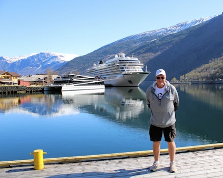 I am standing on the dock at Flam, Norway with our ship, Jupitar, in the background surrounded by mountains.
