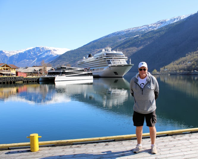 I am standing on the dock at Flam, Norway with our ship, Jupitar, in the background surrounded by mountains.